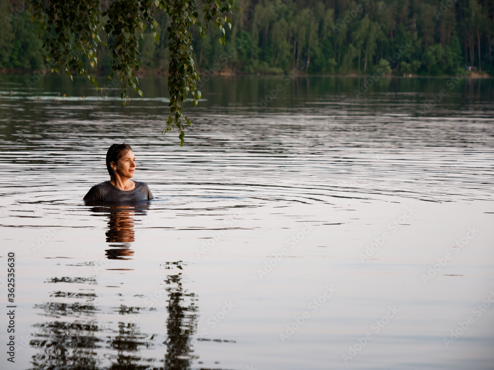 beautiful girl bathes in a lake at sunset