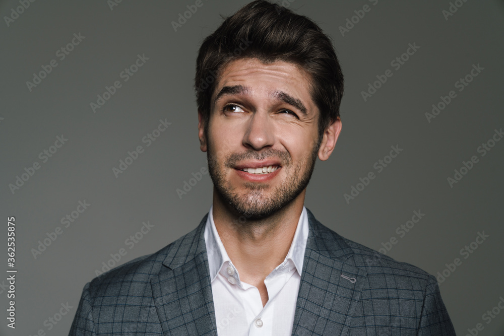 Photo of confused young businessman in jacket posing and looking upward Photo of confused young businessman in jacket posing and looking upward