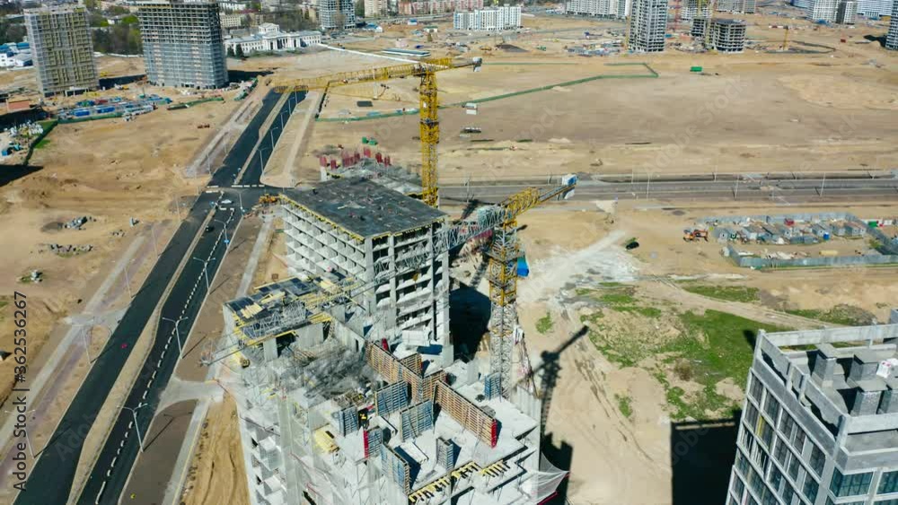 Construction site, aerial view. High cranes works on building site with a houses.
