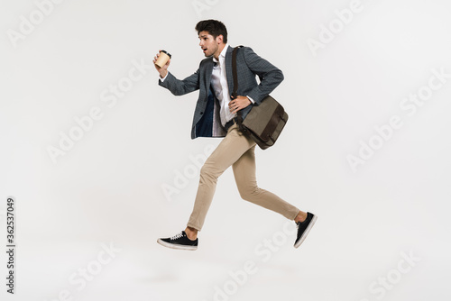 Photo of young businessman drinking coffee while running with bag