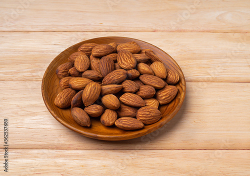 almonds in wood plate on pine wood table .
