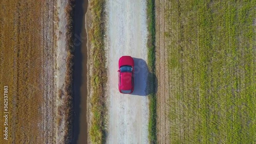 Aerial view of electric suv car driving along to paddy fields in the cloudy morning