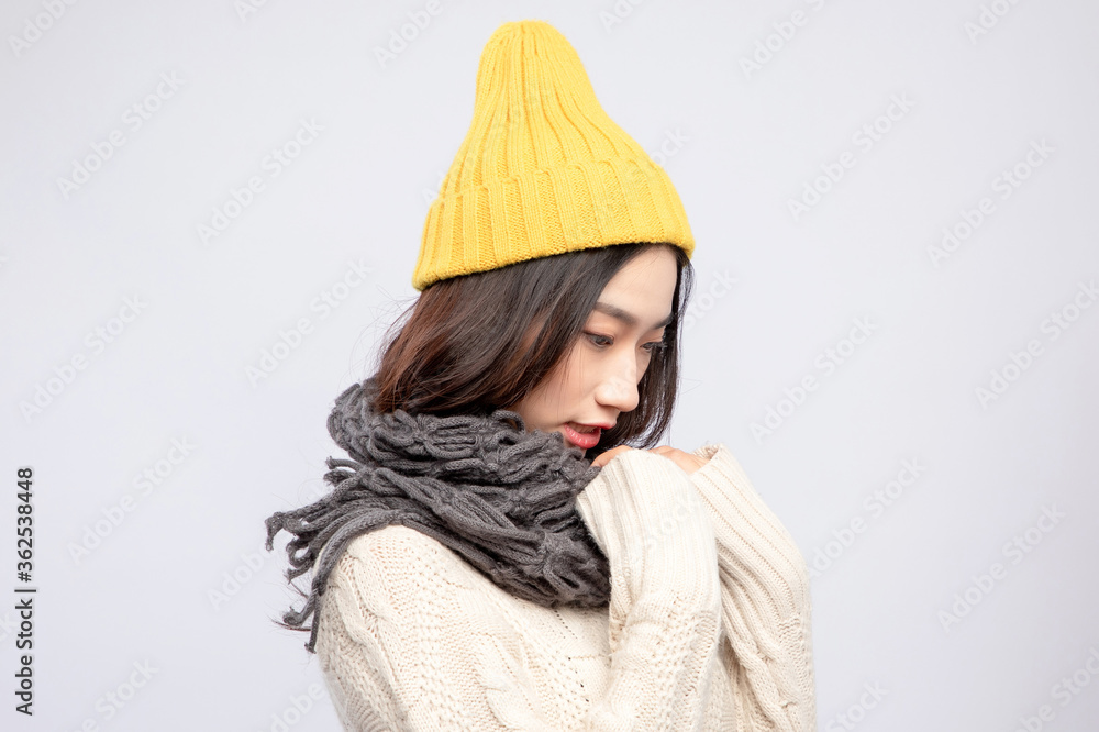 身穿米色毛衣的戴着黄色绒线帽的美丽亚洲女孩