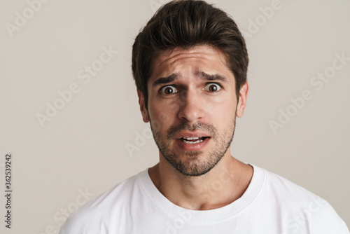Portrait of scared unshaven man expressing surprise on camera