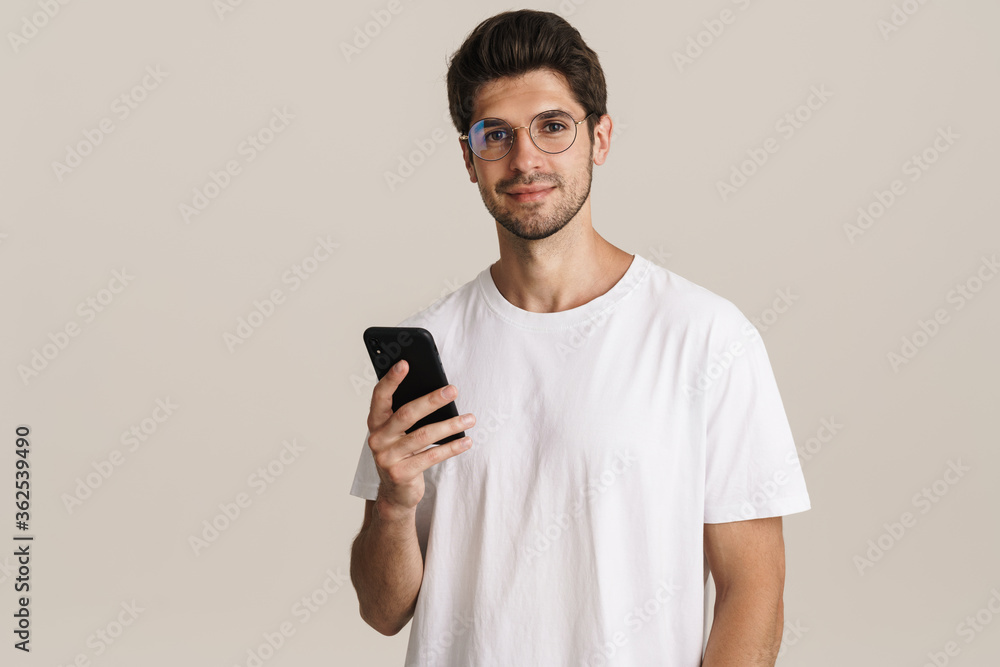 Portrait of pleased handsome man in eyeglasses using mobile phone Portrait of pleased handsome man in eyeglasses using mobile phone