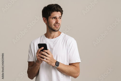 Portrait of displeased man looking aside and using mobile phone