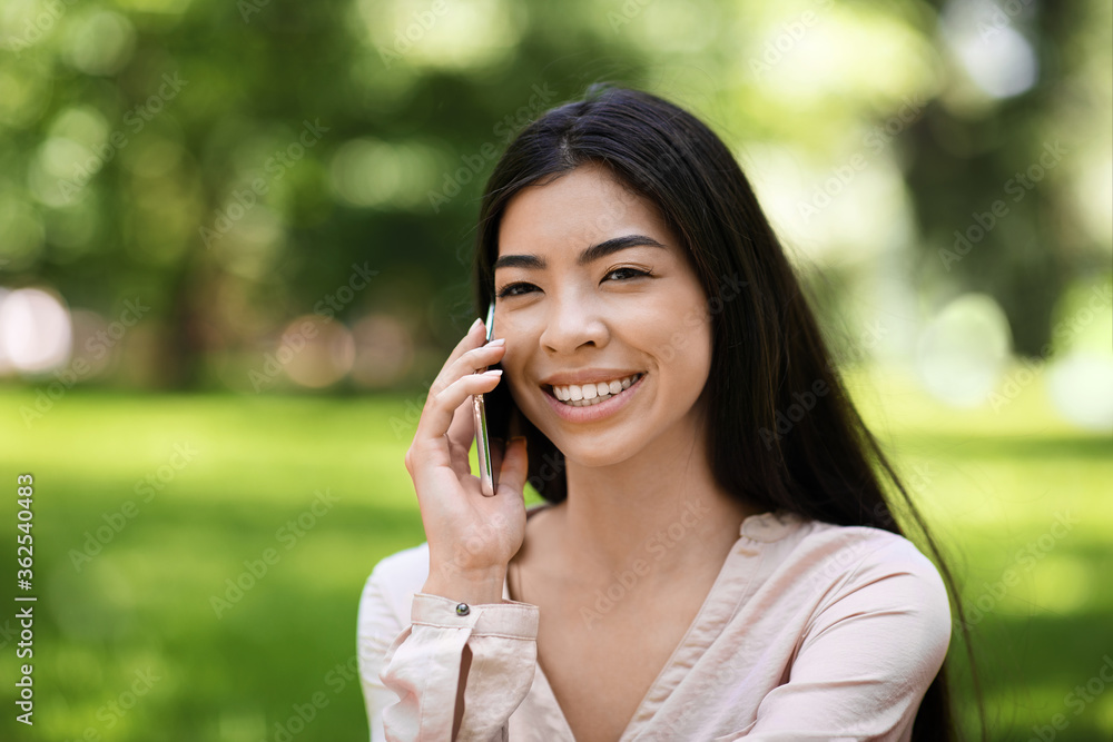 Portrait Of Smiling Asian Girl Talking On Cellphone Outdoors, Relaxing In Park Portrait Of Smiling Asian Girl Talking On Cellphone Outdoors, Relaxing In Park