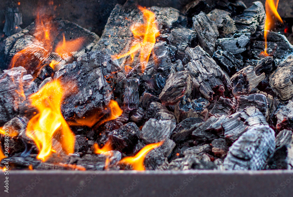 Red-hot pieces of coal and flames in a cooking brazier. Grill with burning coals. Fire and heat. Red-hot pieces of coal and flames in a cooking brazier. Grill with burning coals. Fire and heat.
