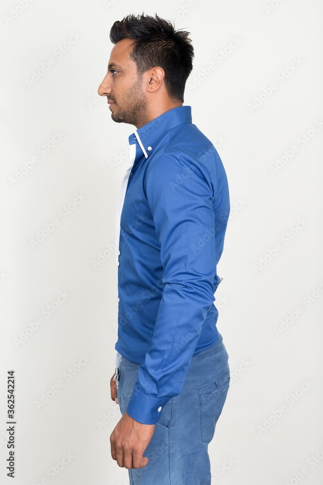 Fototapeta premium Profile view of bearded Indian businessman standing