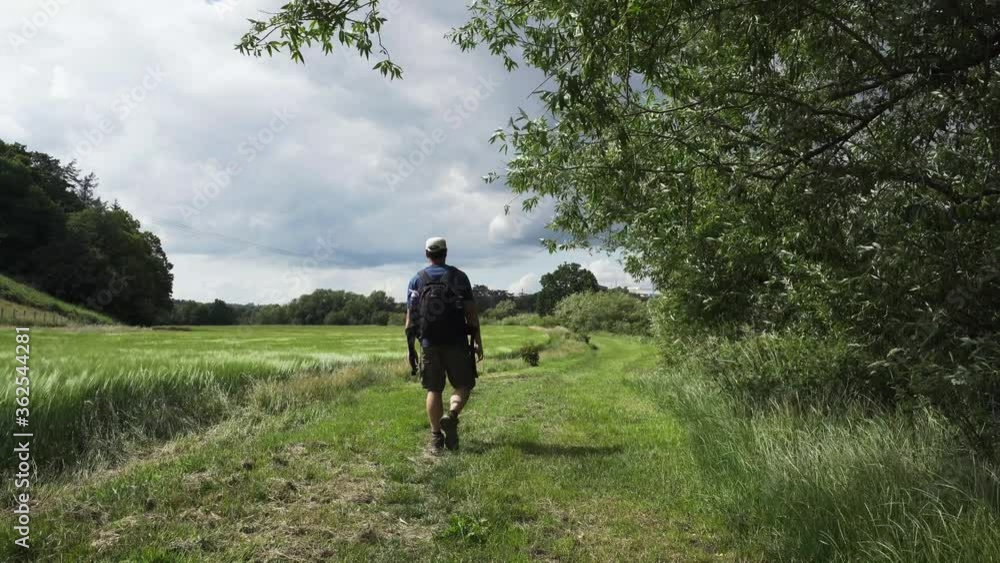 A hiking man walking through a windswept rural scene in the UK A hiking man walking through a windswept rural scene in the UK