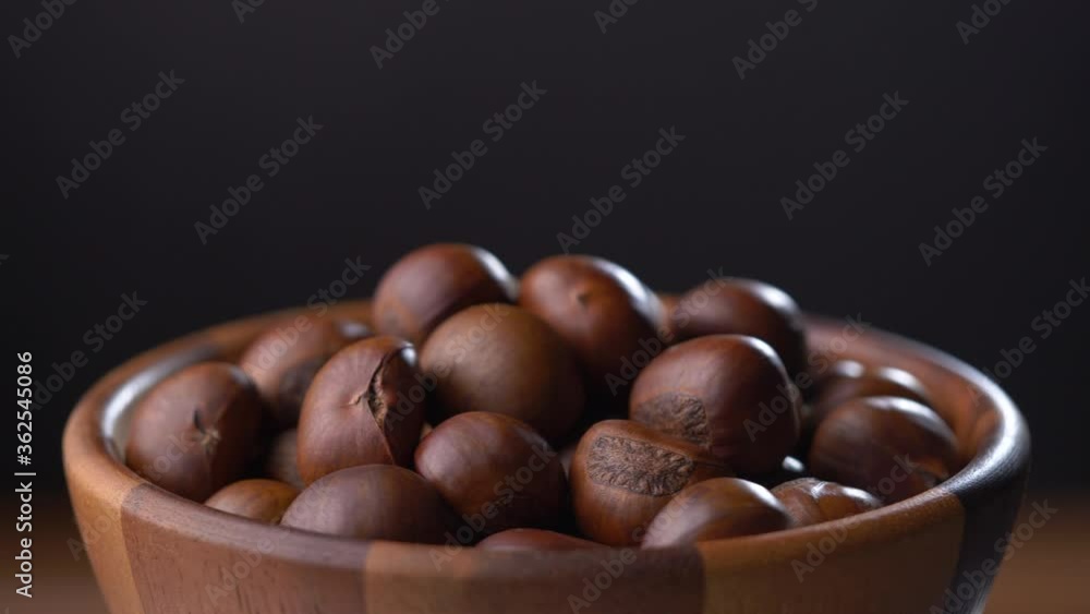 Chestnuts in wooden bowl rotate on black background Chestnuts in wooden bowl rotate on black background