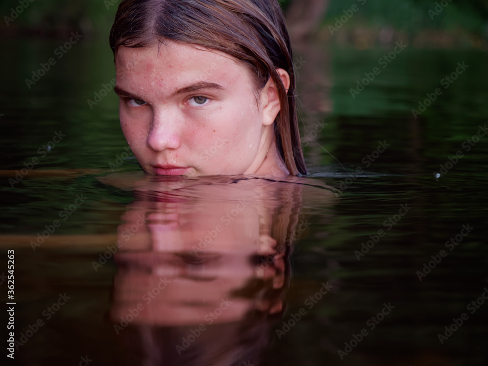 Fototapeta premium mermaid girl in the water among water lilies at sunset
