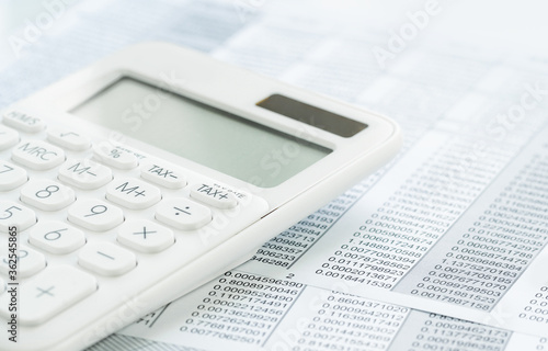 Finance and business concept. White calculator on financial graphs on office desk, spreadsheet. Accounting budgeting or market analysis. Web banner with copy space. Minimal monochrome