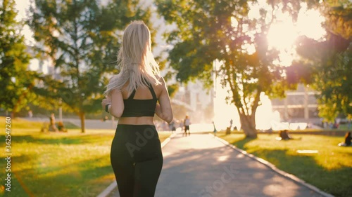 Slim young sexy blonde woman jogging in park, exercising outdoors at sunrise