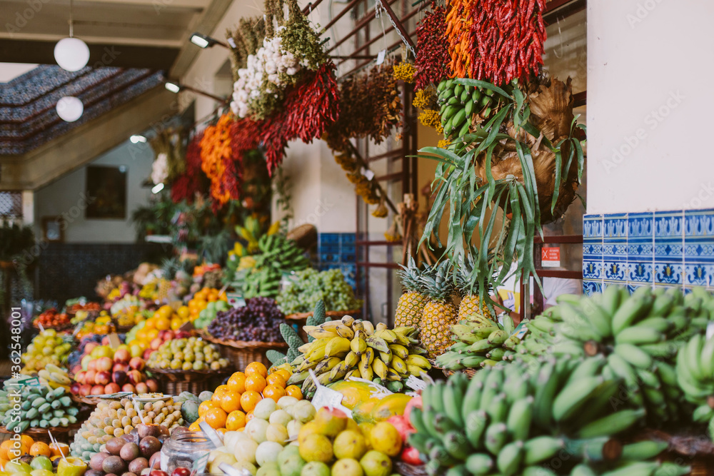 Large market counter with tropical fruits and vegetables. Bright and color photo. Bananas, chili peppers, passion fruit and others.

