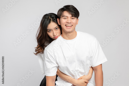 Young Asian lovers embracing in the gray background

