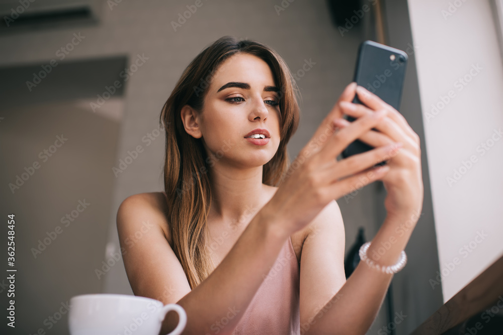 Young woman using smartphone while drinking coffee in cafe Young woman using smartphone while drinking coffee in cafe