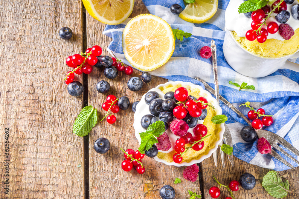 Lemon Mug Cake. Summer sweet dessert in Microwave. Lemon Mug Pies with fresh berries and whipped cream, on wooden background Lemon Mug Cake. Summer sweet dessert in Microwave. Lemon Mug Pies with fresh berries and whipped cream, on wooden background