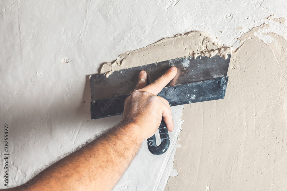 Hand with putty knife repair wall, Hand with a spatula, spatula with spackle paste structure, process of applying layer of putty trowel Hand with putty knife repair wall, Hand with a spatula, spatula with spackle paste structure, process of applying layer of putty trowel