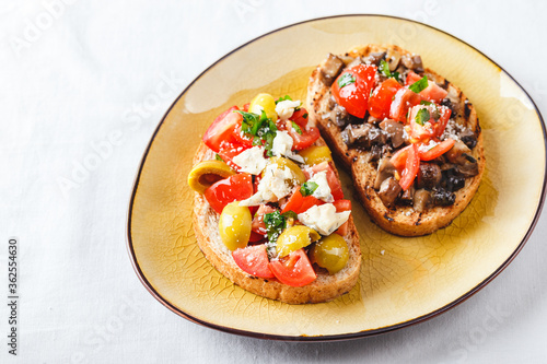 Delicious bruschettas with mushrooms, blue cheese, olives and tomatoes
