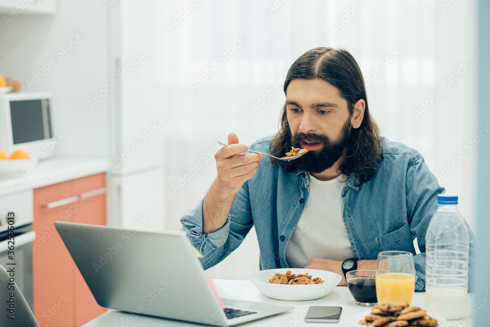 Young man eating cornflakes for breakfast at home Young man eating cornflakes for breakfast at home