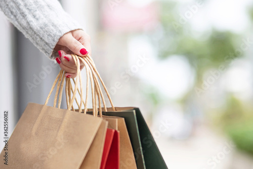 Closeup of woman hand holding shopping bag colorful paper on the street happy summer with copy space