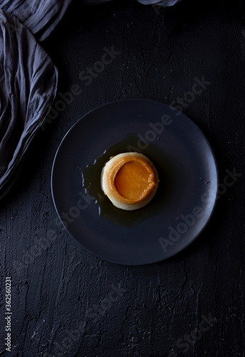 Creme caramel dessert on a black plate. photo