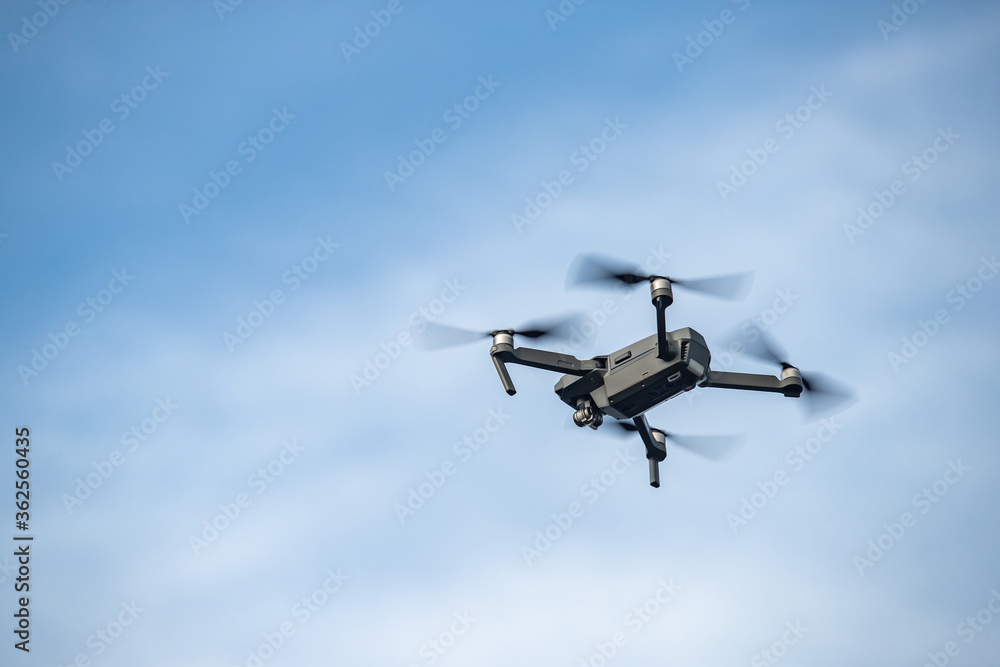 The flying soaring drone in the sky, the blue sky with white clouds, sunny weather, Turning propellers, nobody The flying soaring drone in the sky, the blue sky with white clouds, sunny weather, Turning propellers, nobody