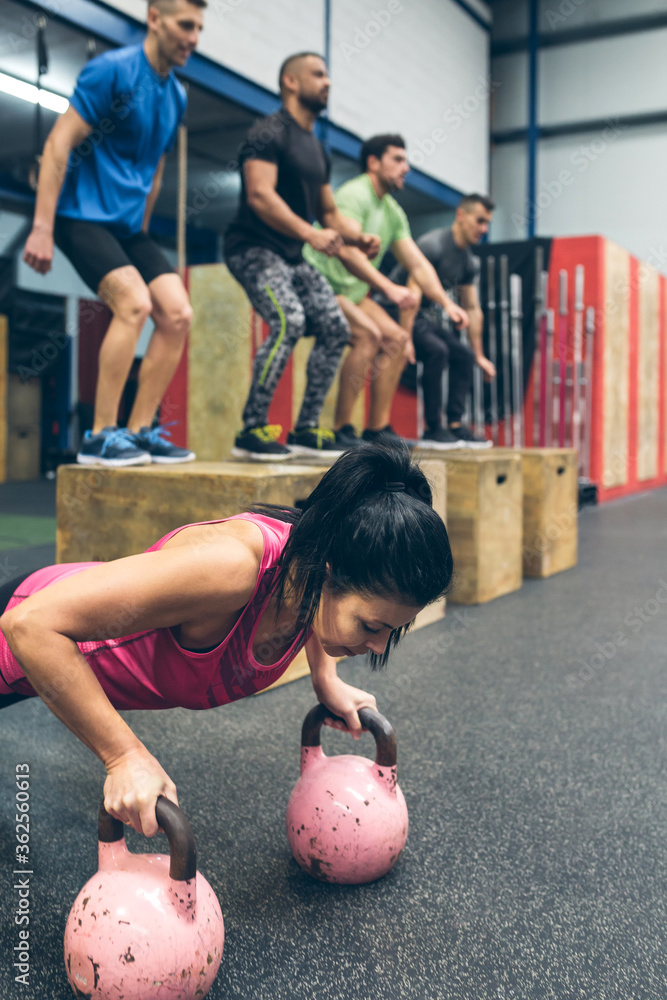 Naklejka premium Sportswoman doing push-ups with kettlebells