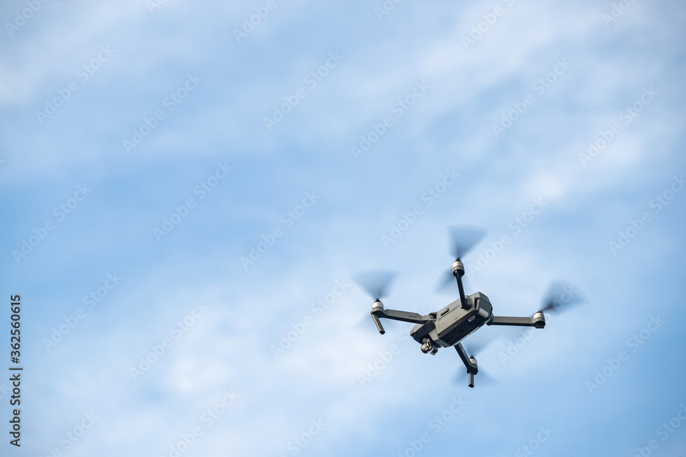 The flying soaring drone in the sky, the blue sky with white clouds, sunny weather, Turning propellers, nobody The flying soaring drone in the sky, the blue sky with white clouds, sunny weather, Turning propellers, nobody