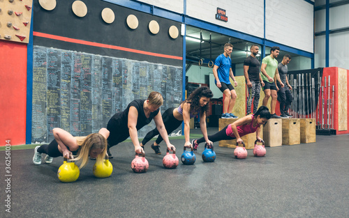 Sportswomen training with kettlebells and sportsmen doing box jumps photo