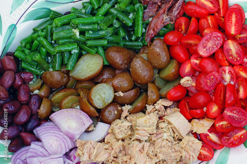 A nicoise salad with canned tuna, anchovies, tomatoes, potatoes and vegetable