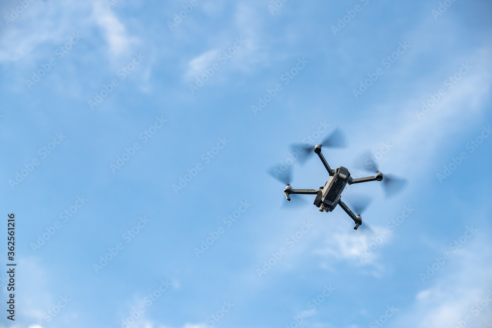 The flying soaring drone in the sky, the blue sky with white clouds, sunny weather, Turning propellers, nobody The flying soaring drone in the sky, the blue sky with white clouds, sunny weather, Turning propellers, nobody