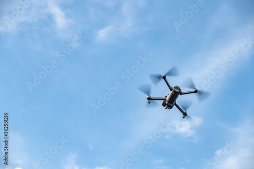 The flying soaring drone in the sky, the blue sky with white clouds, sunny weather, Turning propellers, nobody