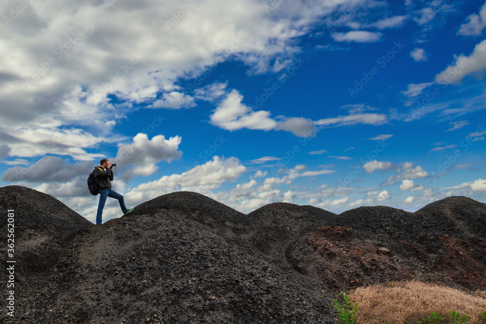 A man with backpack in the mountains is taking pictures of the landscape
