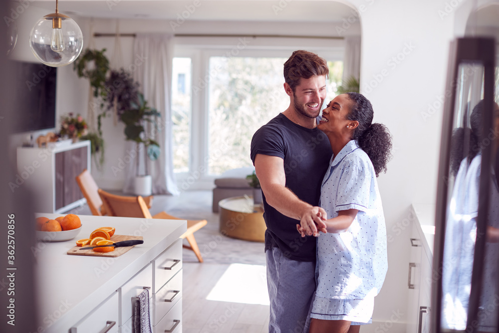 Loving Couple Wearing Pyjamas Having Romantic Dance In Kitchen At Home Together Loving Couple Wearing Pyjamas Having Romantic Dance In Kitchen At Home Together