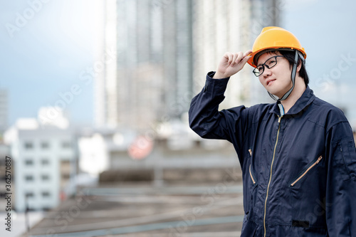 Asian maintenance worker man wearing protective suit and safety helmet working at construction site. Civil engineering, Architecture builder and building service concepts