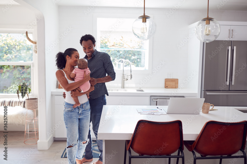 Fototapeta premium Family With Baby Daughter In Kitchen Using Laptop On Counter