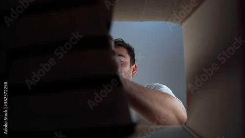 bottom view, packing clothes in the cardboard box, Close-up shot of caucasian man packing clothes, photo