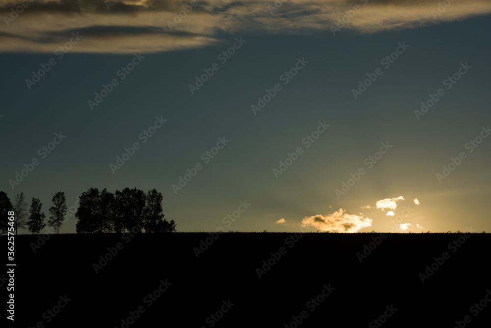 丘に沈む太陽と夕焼け雲