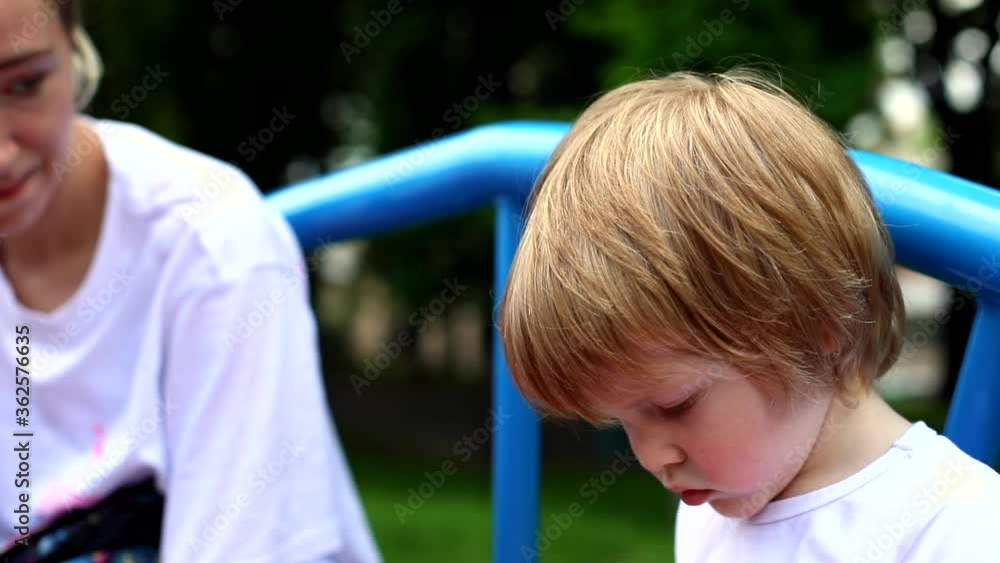 Young mother kissing little son playing outside on kids playground. Happy traveling family. Motherhood vacation. Parenting life. Children activity. Emotional face expression. Serious male child. Young mother kissing little son playing outside on kids playground. Happy traveling family. Motherhood vacation. Parenting life. Children activity. Emotional face expression. Serious male child.