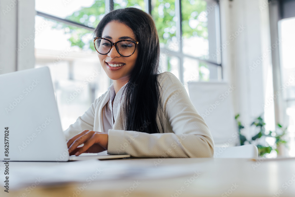 selective focus of smiling businesswoman in glasses using laptop selective focus of smiling businesswoman in glasses using laptop