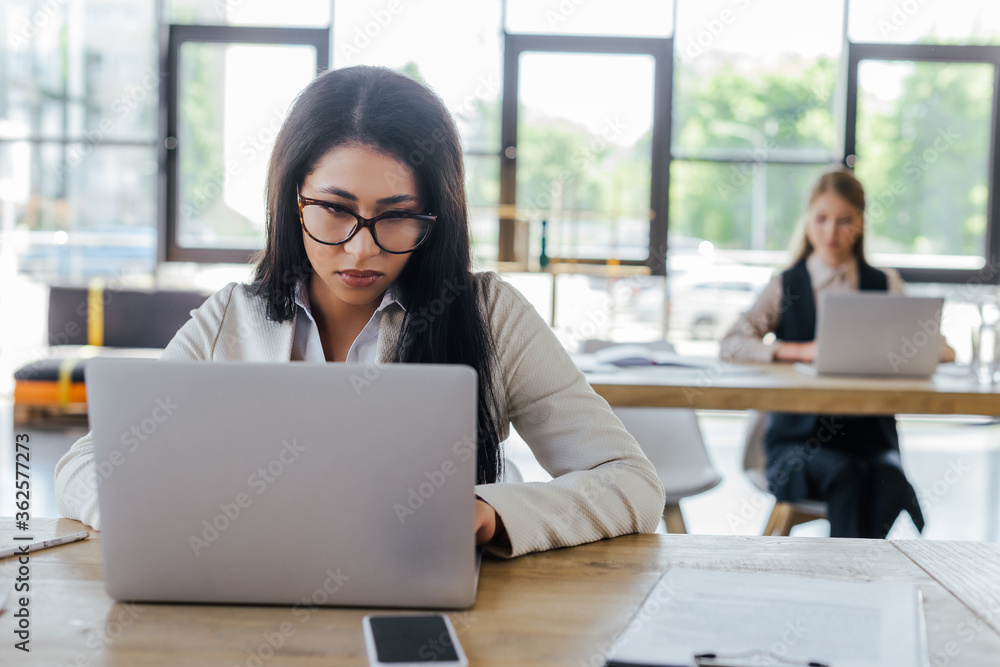 selective focus of businesswoman working near colleague in office selective focus of businesswoman working near colleague in office