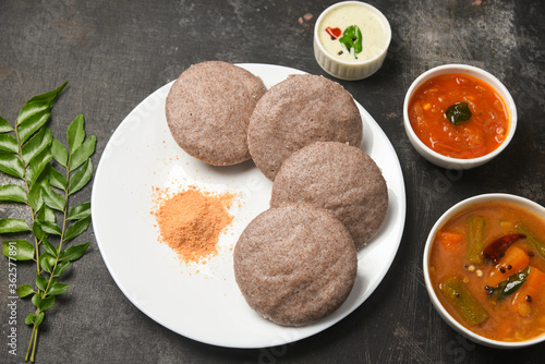 Ragi Idly, finger millet Idli, Sambar, coconut chutney healthy home made breakfast dish Kerala, Karnataka, India. steam cooked finger millet batter. Top view South Indian food dark black background. photo