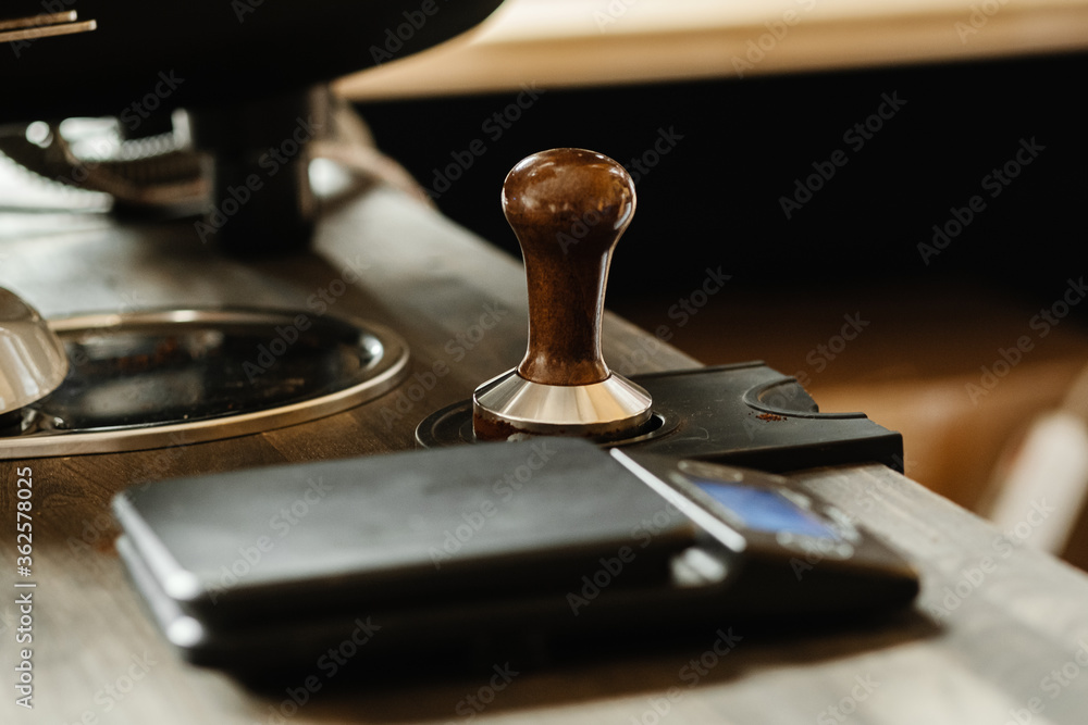 Portafilter and coffee tamper making an espresso coffee. Professional barista working makeing coffee with coffee machine. Hot pouring drink concept. Toned picture