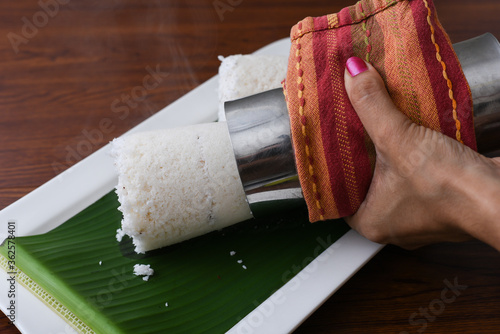 Popular South Indian breakfast puttu / pittu made of white rice flour and coconut in a bamboo mould, with banana, Kerala, India. Bamboo puttu prepared in the bamboo utensil.  photo