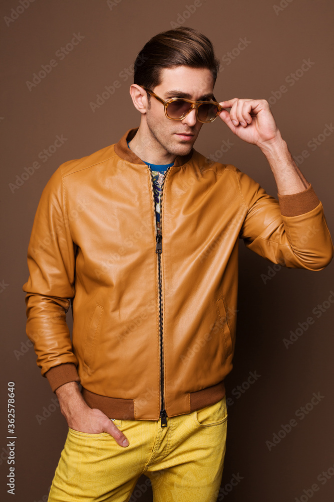 Fototapeta premium The man goes, runs in bright court and bright clothes with prints, yellow jeans and dark glasses. 