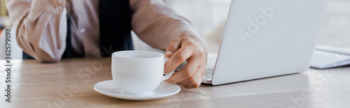 website header of businesswoman touching cup of coffee near laptop