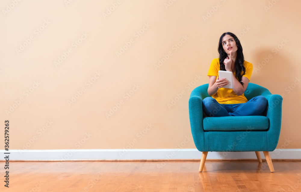 Young woman using her tablet sitting in a chair Young woman using her tablet sitting in a chair