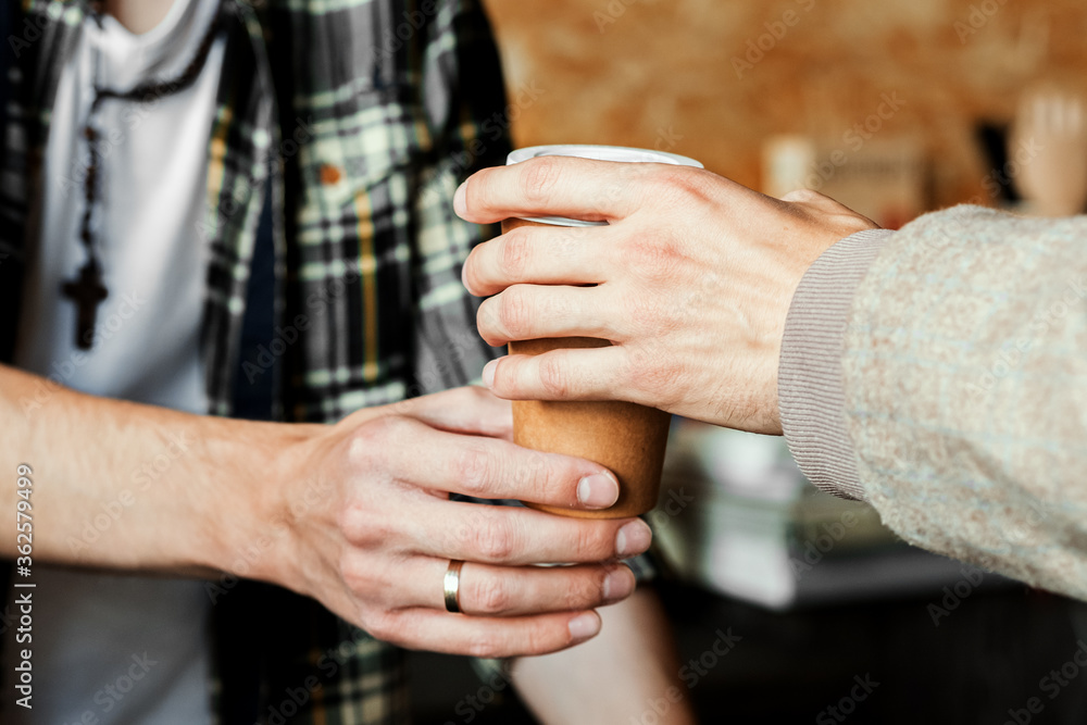 Close up male hand taking cup of hot coffee from barista in confectionary shop or coffee in pub, bar, restaurant. Purchase concept